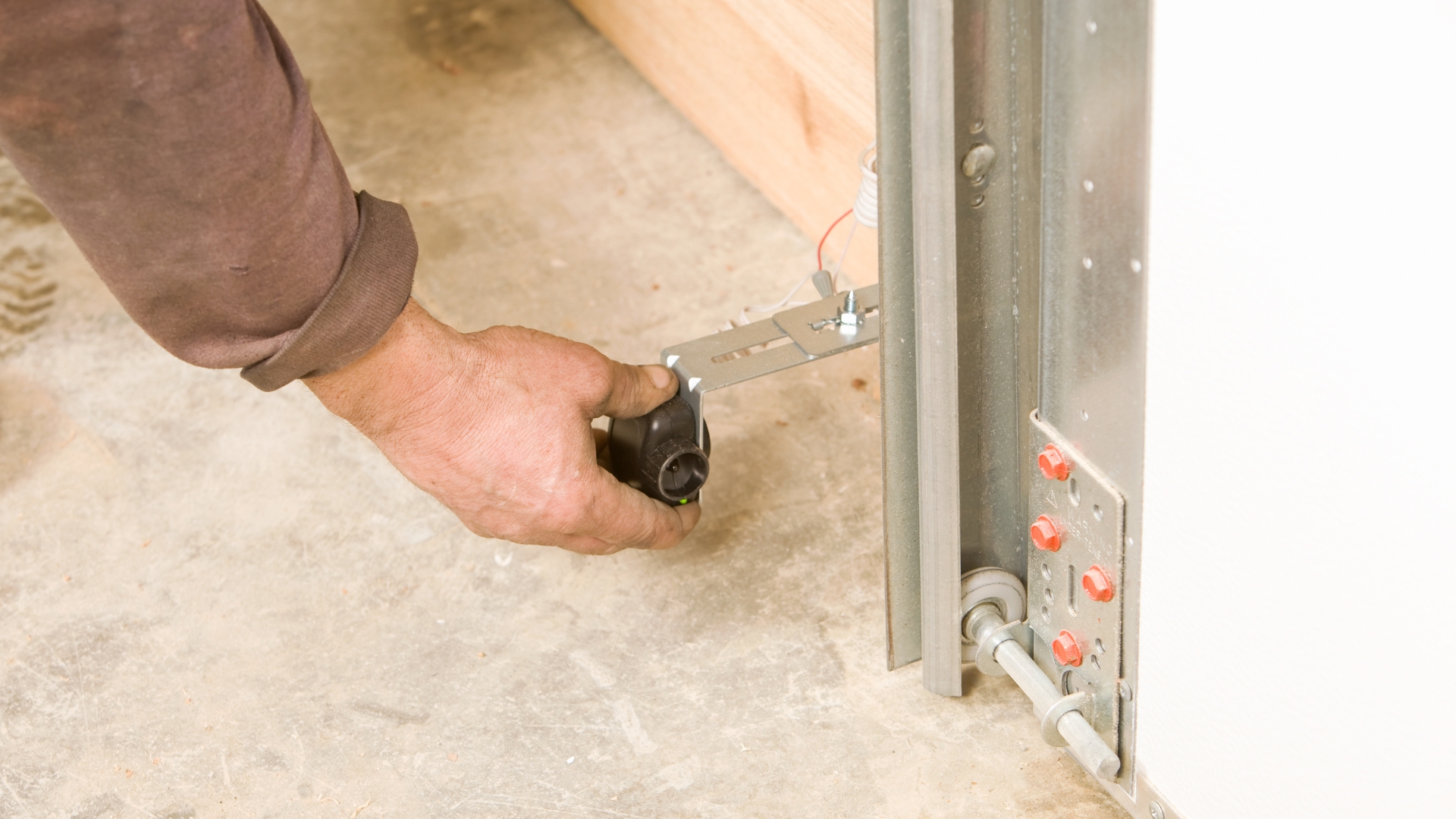 A technician adjusting garage door sensors