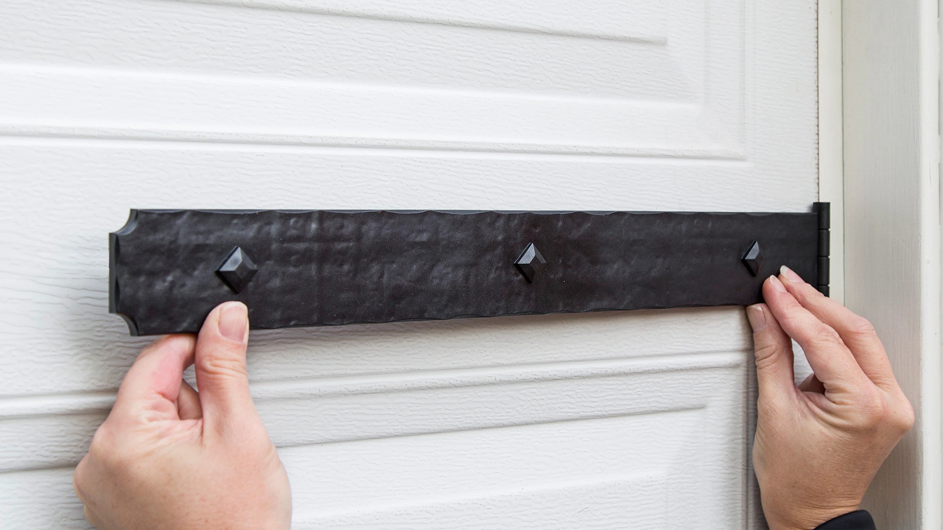 A homeowner installing decorative hardware on their garage door