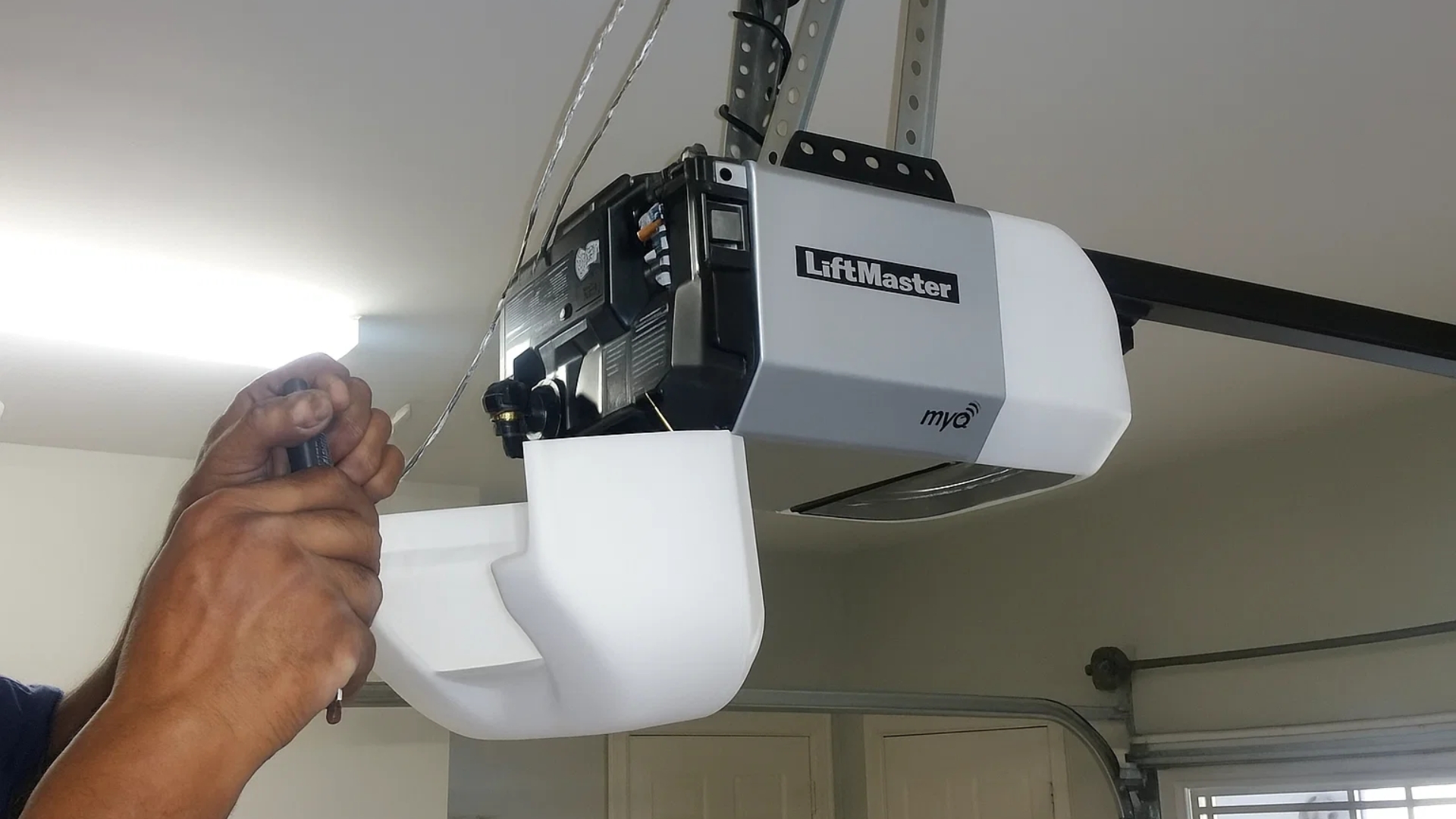 Replacing a garage door opener—technician handling LiftMaster unit installation