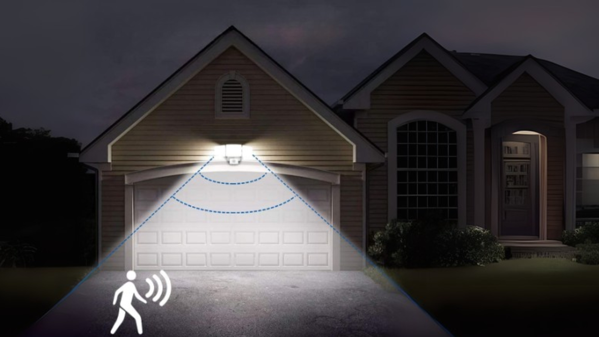 Nighttime view of a home with motion sensor lighting over the garage door